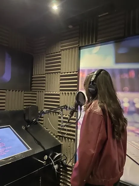 Sarea Sohail at the microphone in her studio, headphones on